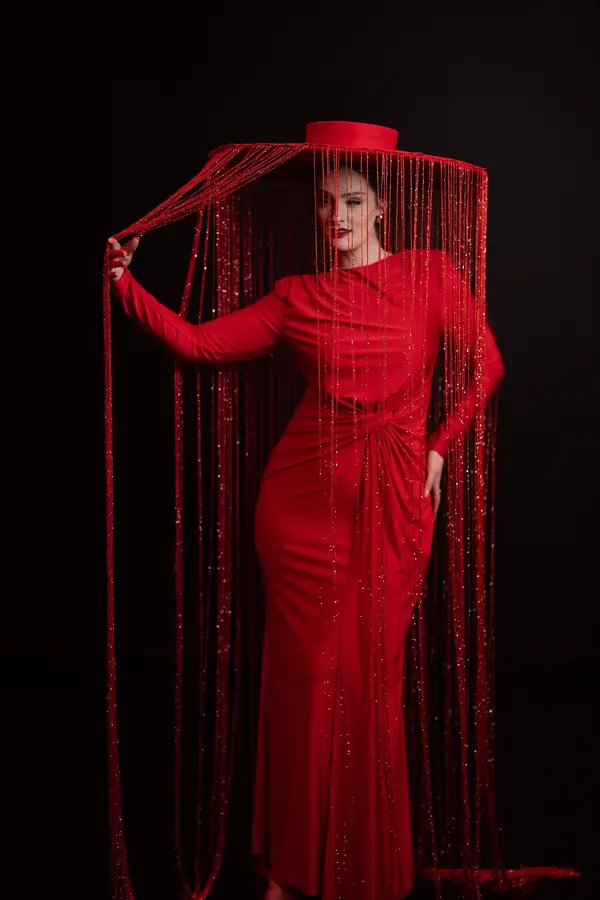 Studio portrait of a woman in a red gown framed by red fringe